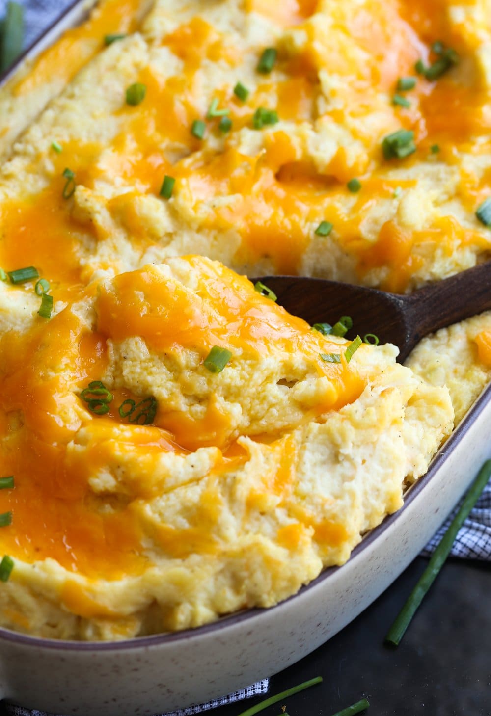 Serving cheesy baked mashed potatoes in a casserole dish