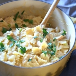 Bowl of cheesy chicken and bow tie pasta with parsley