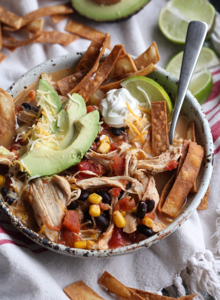 Chicken Tortilla Soup garnished with avocado, chips, sour cream, and lime