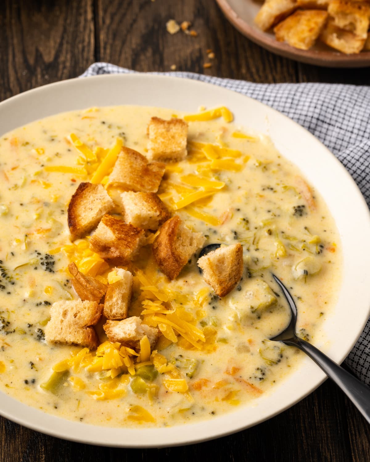 A bowl of instant pot broccoli cheddar soup topped with croutons with a spoon.